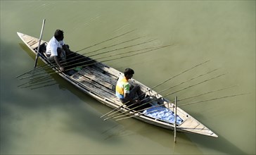 Fishermen fishing sitting on a boat in a lake using fishing rods at a village in Barpeta district