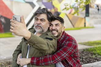 Happy gay couple taking a break on the street and taking a selfie