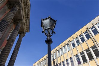 An old lantern stands between a prefabricated building of the Potsdam University of Applied