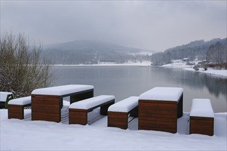 Rest area with snow-covered benches at the Hennesee, Hennetalsperre, Naturpark