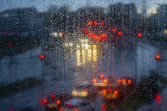 Rainy weather, road traffic, raindrops on a window pane, behind, blurred, lights of vehicles on a