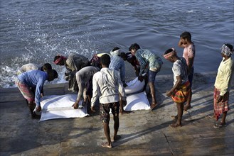 Public Works Department (PWD) of Assam labourer throwing sand bag from boat in the banks of Beki