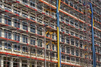 Large construction site, scaffolded shell of an office building complex, air hoses for building