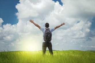 Backpacker man in the field spreading his hands, concept of successful man spreading his hands