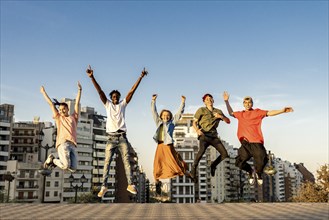 Group of young beautiful multiethnic man and woman friends having fun jumping outdoor in the city,