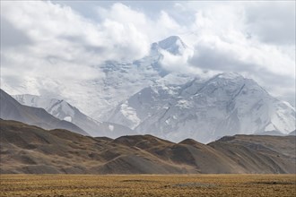 Glaciated, cloud-covered mountain peaks and golden meadows, Lenin Peak, Trans Alay Mountains, Pamir