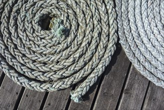 Close up of two coiled braided ropes, plaited hawsers on deck