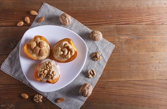 Persimmon dessert with curd, nuts and milk cream on brown wooden background. top view, copy space