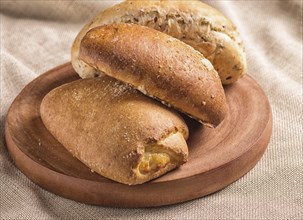 Sweet buns on a wooden board and linen tablecloth