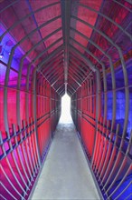 A long tunnel with red lighting and metallic structures conveys a futuristic and industrial