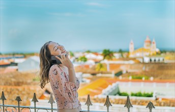 Happy girl talking on the phone at the viewpoint in Granada, Nicaragua. Nicaraguan woman talking on