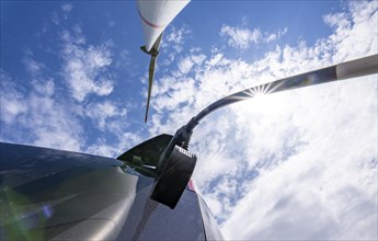 Wind turbine, technician charging his electric car during wind turbine maintenance, directly at the