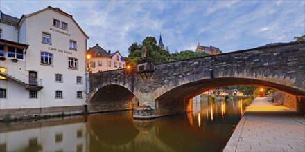 Town view of Vianden with the old stone bridge over the river Our and the castle in the evening,