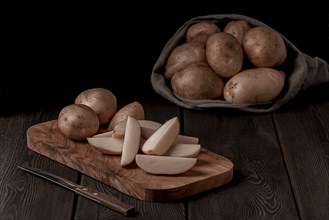 Raw potatoes, sliced, on a wooden table, top view, no people