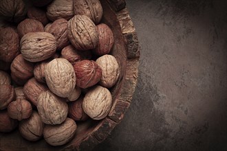 Fresh walnut in a shell, wooden plate, top view, no people