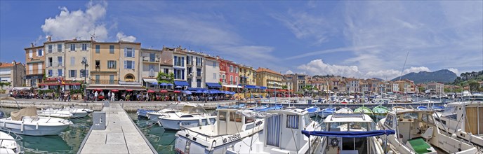 A picturesque harbour with numerous boats, colourful buildings and restaurants under a blue sky