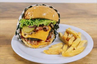 Delicious homemade hamburger on a plate on a wooden table. Big cheeseburger with french fries