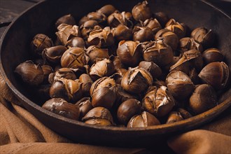 Roasted chestnuts, in an iron pan, wooden table, top view, no people, rustic style