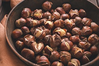 Roasted chestnuts, in an iron pan, wooden table, top view, no people, rustic style