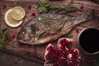 Fried dorado fish, with spices and herbs, on a wooden board, pomegranate sauce, close-up, no people