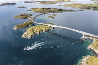 Aerial view of bridge connecting islands at the norwegian coast, fishing boat passing below the