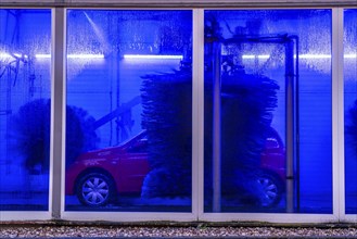 Car in an automatic car wash, car wash tunnel, cleaning foam is sprayed on, rotating brushes clean