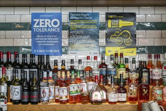 Alcohol bottles and posters about community charter for responsible drinking, Wetherspoon bar,