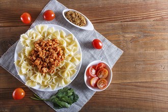 Farfalle bolognese pasta with minced meat on brown wooden background. top view, copy space