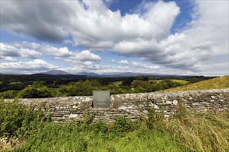 Memorial plaque in old stone wall overlooking rolling countryside, graveyard, St Garmons Church,