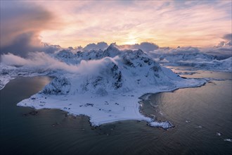 View of Flakstad and Skagsanden beach, snow-covered mountains and fjord at sunset, aerial view,