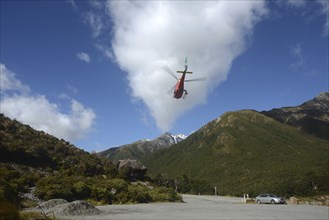 ARTHURS PASS, NEW ZEALAND, 2021-01-29: A brightly painted helicopter takes off from a car park in