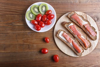 Smoked salmon sandwiches with butter on wooden background. cherry tomatoes. top view, copy space