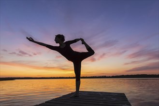 Woman practicing yoga posture Natarajasana, Lord of the Dance Pose, one legged standing, balancing,