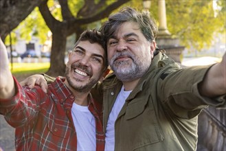 Happy married gay couple taking a selfie in the park