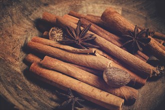 Cinnamon sticks, with nutmeg and anise star, in a wooden plate, top view, no people