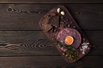 Beef tartare, with egg, capers, gherkins and bread, toned, top view, close up, horizontal, no