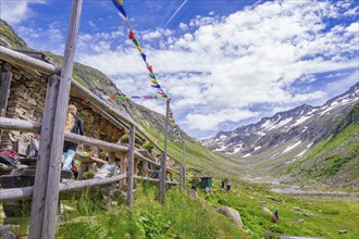 Scenery with a mountain farm, colourful flags and a path through the green mountain landscape under