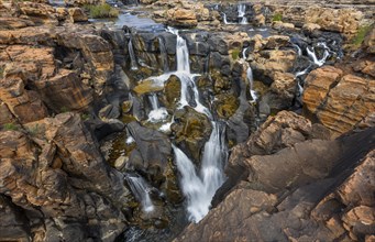 Waterfalls between orange-coloured rocks on the Treur River, Bourke's Luck Potholes, long exposure,