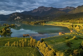 Aerial view of a lake in front of mountains, sunrise, spring, dark clouds, Lake Kochel, foothills