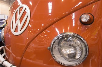 The front end of a Volkswagen bus with large VW logo, indicators and headlights. Techno Classica is