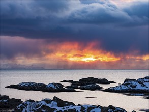 The sun shines through dense clouds on the coast of Ballstad, Vestvagoy Island, Lofoten, Norway,