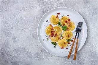 Fresh ravioli, with butter, spices and herbs, fried bacon, on the table, top view, light