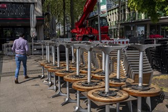 Stacked chairs and tables from various catering establishments, on Kennedyplatz, closed cafes,