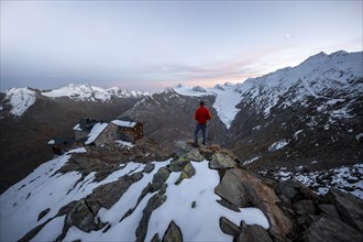 Hiker looking at mountain panorama and glacier, mountain hut Ramolhaus in autumn with snow, at