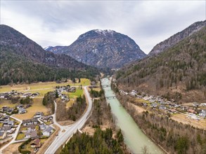 Aerial view of a rural area with a river flowing past a settlement and surrounded by mountains