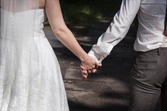 A bride and groom walk hand in hand to their church wedding on 14 June 2016