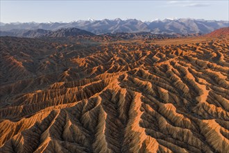 Landscape of eroded hills, badlands at sunset, mountain peaks of the Tian Shan Mountains in the