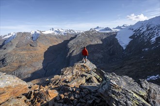 Mountaineer standing on a rock, surrounded by an impressive mountain landscape with snow-covered