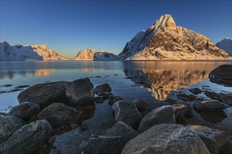 Snow-covered mountains reflected in the fjord at sunrise, winter, Reine, Moskenesoya, Lofoten,