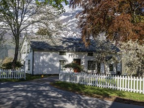 View of snow-covered mountains, white wooden house, spring, Hardangerfjord near Lofthus, Hardanger,